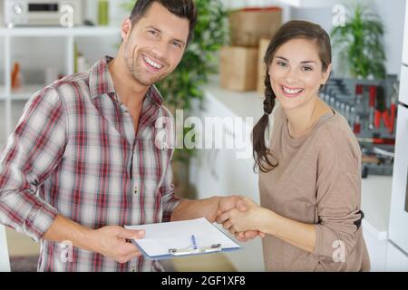 femme reconnaissante poignée de main avec un plombier souriant Banque D'Images