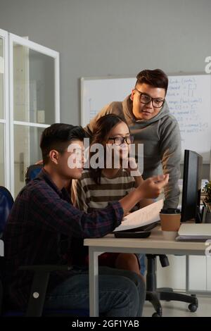 Étudiant en informatique expliquant son idée créative à des amis lorsqu'ils travaillent sur un projet de groupe Banque D'Images
