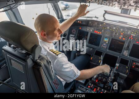 Vue en grand angle d'un pilote professionnel assis dans une cabine d'avion, prêt pour le décollage Banque D'Images