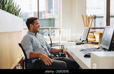 Le responsable prend une pause et regarde en souriant. Entrepreneur assis détendu au bureau. Banque D'Images