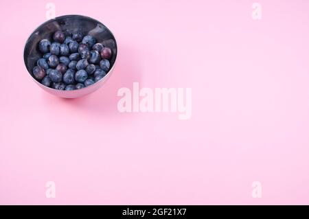 Vue de dessus d'un petit bol en céramique de métal rempli de bleuets mûrs frais isolés sur fond rose Banque D'Images