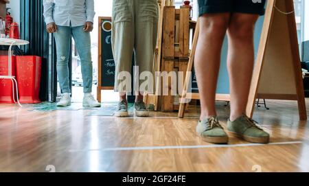 Des personnes méconnaissables font la queue pour garder la distance entre les réseaux sociaux Banque D'Images