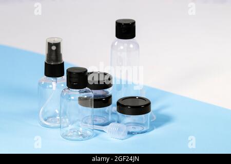 Groupe de bouteilles de voyage en plastique transparent pour cosmétiques : savon, gel, lotion, crème, shampooing, Maquillage et liquides sur fond bleu clair. Voyages modernes Banque D'Images