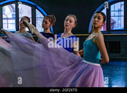 Quatre jeunes danseuses de ballet vêtues de tutus colorés pour une représentation dans une salle de répétition Banque D'Images