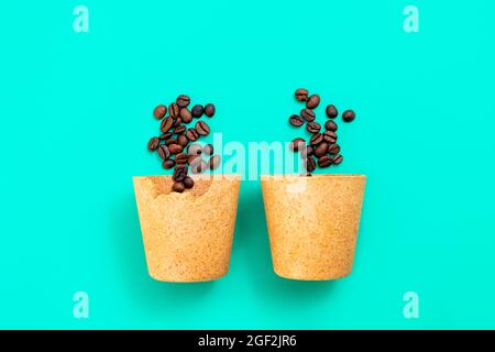 Deux tasses de café écologique comestibles que vous pouvez manger après avoir bu, faites à partir de gaufres, avec des grains de café sur fond vert. Concept zéro déchet, pose à plat Banque D'Images