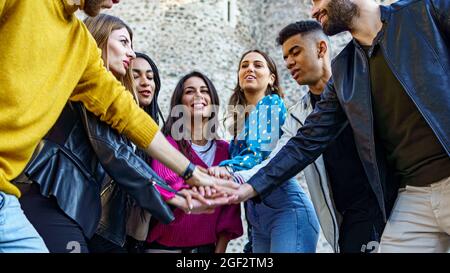 Gen z jeunes qui s'amusent à se joindre entre les mains en plein air. Unité, confiance et amitié. Banque D'Images