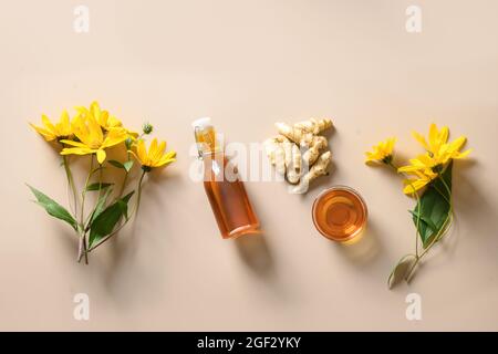 Sirop d'artichaut Jérusalem en bouteille, fleurs et racine sur fond beige. Succédanés de sucre pour desserts végétaliens crus. Banque D'Images