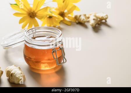 Sirop d'artichaut Jérusalem en bouteille, fleurs et racine sur fond blanc. Succédanés de sucre pour desserts crus. Banque D'Images