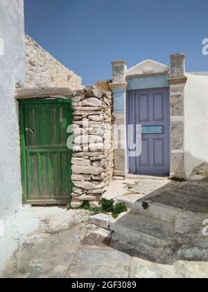 Île Amorgos, Grèce. Vieilles maisons colorées dans le village traditionnel. Portes peintes de couleurs vives dans une allée. Prise de vue verticale, ciel bleu et espace de copie Banque D'Images