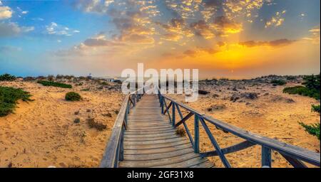 Dunes de sable donnant accès à la plage de la Barrosa à Sancti Petri au coucher du soleil, Cadix, Espagne. Banque D'Images