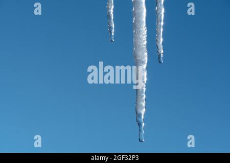 Au printemps, les glaces se fondent et s'égoutter contre le ciel bleu. Météorologie, réchauffement de la planète et fonte de la neige et de la glace. De l'eau coule dans le ciel. Banque D'Images