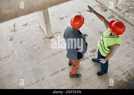 Vue de dessus de deux ouvriers de la construction portant des casques de sécurité sur le site de la construction, espace de copie Banque D'Images