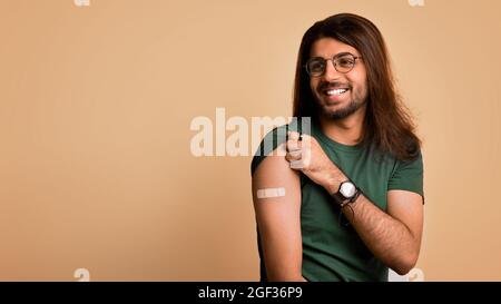 Un homme arabe heureux s'est fait vacciner, montrant l'épaule avec du plâtre Banque D'Images