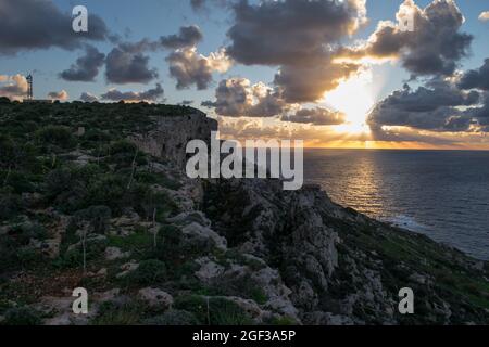 MELLIEHA, MALTE - 04 janvier 2021 : un coucher de soleil, vu du sommet d'une falaise le long de la côte dans la partie nord de Mellieha, Malte. Station radar visible n Banque D'Images