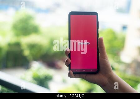 Main tenant un téléphone mobile avec le logo de l'application zomato montrant cette entreprise de technologie alimentaire unicorn qui a récemment lancé un IPO Banque D'Images