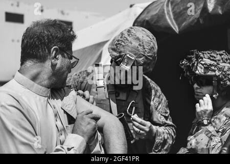 Un Corpsman affecté à la 24e unité expéditionnaire maritime (MEU) et un Medic affecté à la 82e Division aéroportée assiste un évacuateur lors d'une évacuation à l'aéroport international Hamid Karzaï, Kaboul, Afghanistan, août 22. Les membres du service américain aident le ministère d'État à effectuer une opération d'évacuation non combattantes (NEO) en Afghanistan. (É.-U. Photo du corps marin par Sgt. Isaiah Campbell via American PhotoArchive/Alamy) Banque D'Images