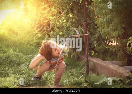 jolie fille buvant de l'eau du robinet à la campagne Banque D'Images