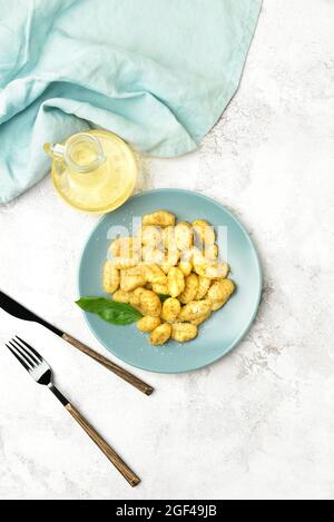 Assiette avec délicieux gnocchi de pesto sur fond clair Banque D'Images