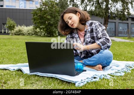 Une écolière regarde une classe Internet et étudie à distance. La fille utilise les technologies Internet sans fil. Une jolie jeune fille adolescente assise sur le Banque D'Images