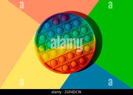 Jouet antistress en silicone rond le pop-it sur le fond coloré arc-en-ciel. Banque D'Images