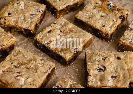 Beurre brun Bourbon morceau de chocolat pacane Blondies garnies de sel de mer feuilleté: Blondies coupées en carrés et servies sur papier kraft brun Banque D'Images