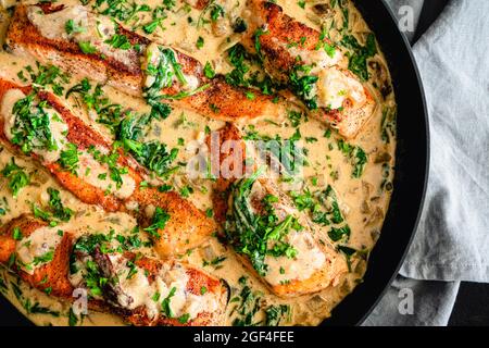 Beurre crémeux à l'ail saumon toscan dans une poêle : filets de saumon dans une sauce crémeuse au parmesan avec épinards et tomates séchées Banque D'Images