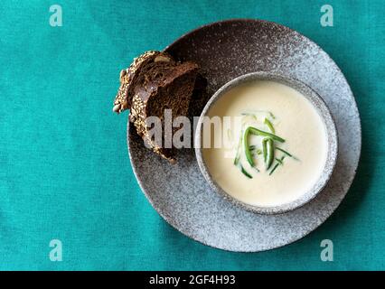 Bol en argile de soupe à la crème de saumon finlandaise servi avec du poireau et des croûtons sur fond vert de nappe. Concept d'alimentation saine. Arrière-plan alimentaire avec espace de copie. Gros plan, mise au point sélective. Banque D'Images