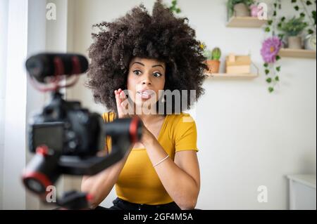 Jeune femme enregistrant sur l'appareil photo tout en vlogging à la maison Banque D'Images