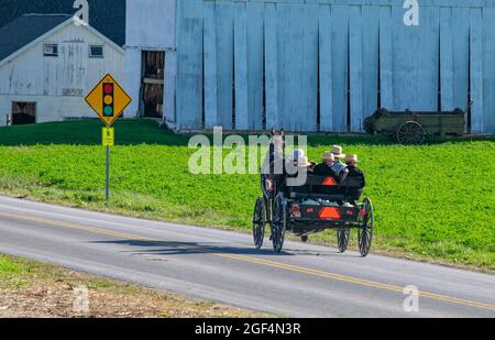 Ouvrez Amish Horse et Buggy avec une promenade en famille en voyage loin de Camera sur une route de campagne en une journée ensoleillée Banque D'Images