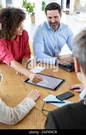 Femme d'affaires discutant avec ses collègues en réunion sur une tablette numérique Banque D'Images