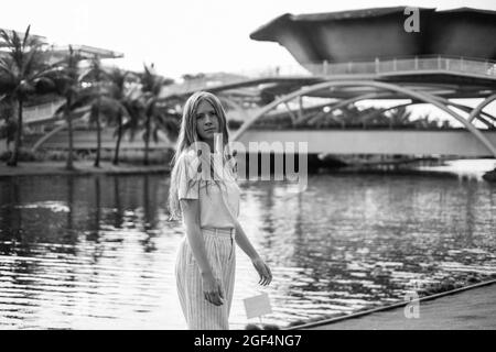 Photo en noir et blanc de la jolie jeune femme caucasienne marchant dans la ville. Été. Vêtements décontractés. Palmiers. Photo de haute qualité Banque D'Images