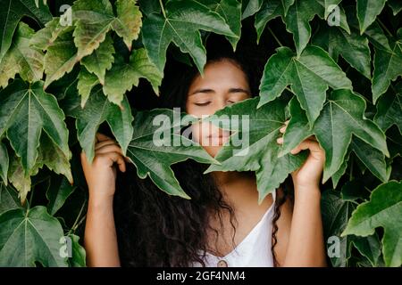 Femme avec les yeux fermés au milieu des feuilles Banque D'Images