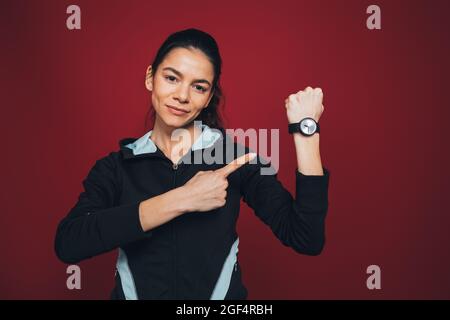 Femme sportive de taille moyenne montrant sa montre sur fond de marron Banque D'Images
