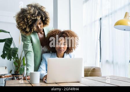 Jeunes femmes indépendants travaillant ensemble sur ordinateur portable à la maison Banque D'Images