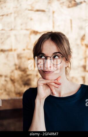 Jeune femme avec main sur le menton faisant le visage Banque D'Images
