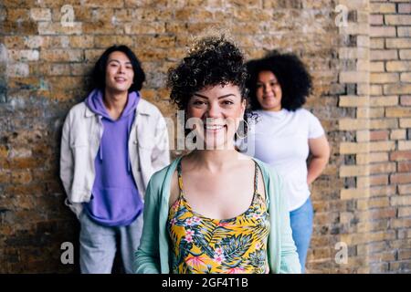 Jeune femme aux cheveux bouclés debout devant des amis Banque D'Images