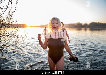 Femme âgée en maillot de bain debout dans l'eau le matin Banque D'Images