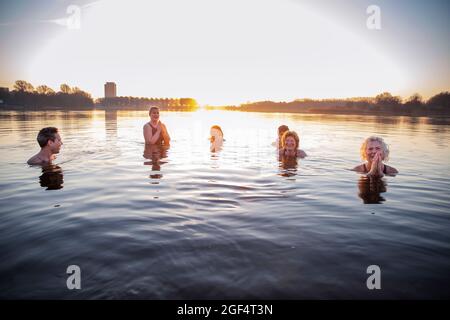 Souriantes femmes méditant tout en s'amusant avec des amis masculins dans l'eau Banque D'Images