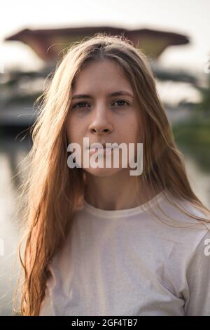 Portrait en gros plan de la belle femme caucasienne avec des cheveux blonds dans le parc. Sans maquillage. Vent dans ses cheveux. Belle lumière du soleil. Photo de haute qualité Banque D'Images