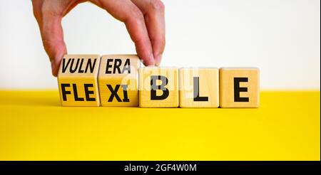 Symbole vulnérable ou flexible. Homme d'affaires transforme les cubes en bois et les mots « vulnérable » en « flexible ». Magnifique arrière-plan blanc, espace de copie. Unité commerciale Banque D'Images
