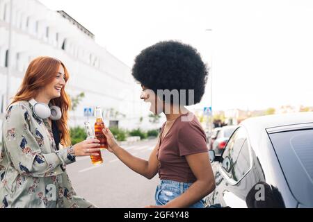 Gaie Afro femme toaster des bouteilles de bière avec une amie au bord de la route Banque D'Images