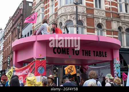 Londres, Angleterre, Royaume-Uni 23 août 2021 extinction rébellions Impossible la rébellion commence à Trafalgar Square, marchant vers le Strand, bloquant l'intersection de long Acre et de St Martins Lane avec une table et des chaises roses géants, des orateurs dont le comédien Mark Thomas s'est adressé à la foule assemblée Credit: Denise Laura Baker/Alay Live News Banque D'Images
