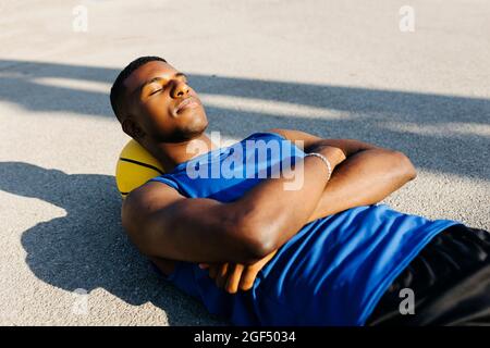 Un jeune homme se reposant tête sur un terrain de basket-ball tout en étant allongé sur un terrain de sport Banque D'Images