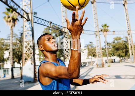 Homme tournant le ballon de basket à la main sur le terrain de sport Banque D'Images