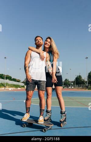 Un jeune couple souriant se tient aux mains du terrain de basket-ball par beau temps Banque D'Images
