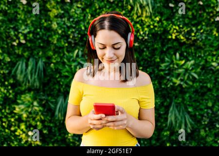 Une jeune femme écoute de la musique à l'aide d'un casque tout en utilisant un smartphone Banque D'Images