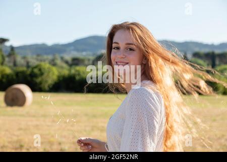 Souriante belle jeune femme rouge sur le terrain Banque D'Images