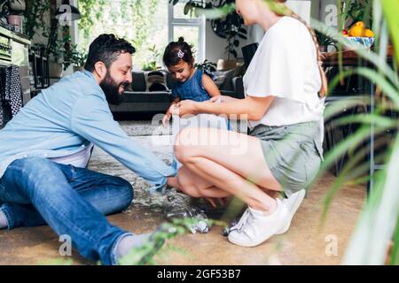 Homme souriant ramassant la bouteille de déchets avec la famille à la maison Banque D'Images