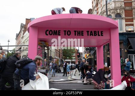 Londres, Angleterre, Royaume-Uni 23 août 2021 extinction rébellions Impossible la rébellion commence à Trafalgar Square, marchant vers le Strand, bloquant l'intersection de long Acre et de St Martins Lane avec une table et des chaises roses géants, des orateurs dont le comédien Mark Thomas s'est adressé à la foule assemblée Credit: Denise Laura Baker/Alay Live News Banque D'Images