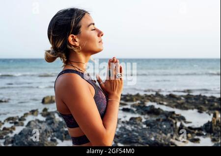 Jeune femme aux mains classé méditant à la plage Banque D'Images
